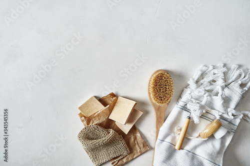 Care in the home. Soft Terry cotton towel with fringe, natural brush, facial massager, organic sponge and soap on a light background, top view. Cozy style.