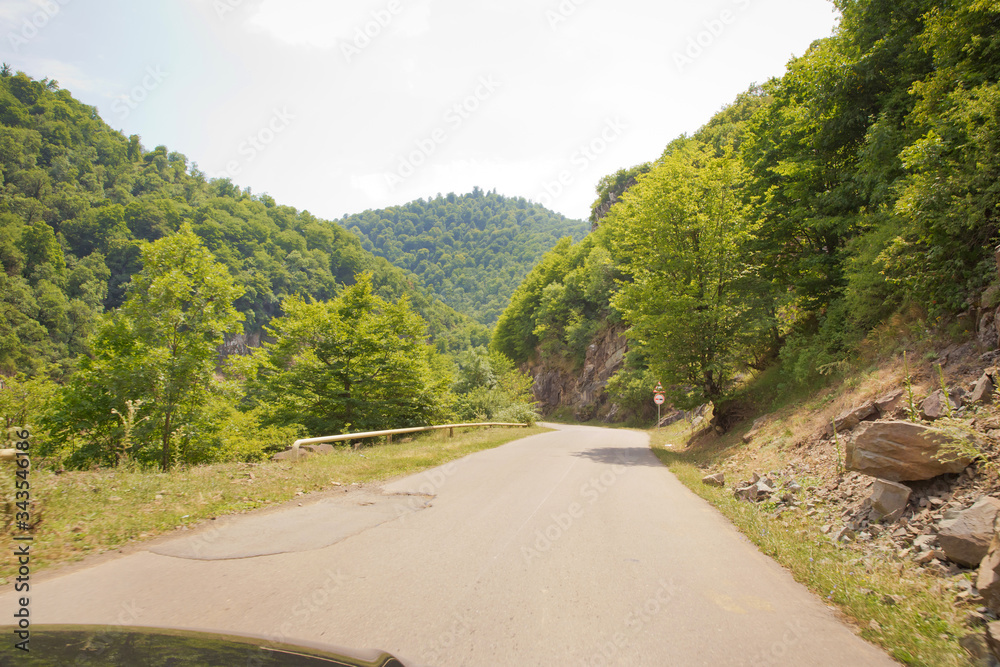 Mountain road between forests . Winding mountain road . A road in Azerbaijan between Forest . Empty road in mountainous area along mountains . highway and mountain with beautiful clouds landscape.