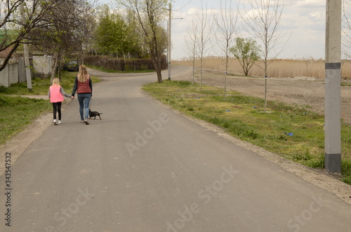 Family holiday. Mom and daughter walk a dachshund dog on the lake.