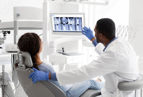 Dentist Explaining Xray On Screen To Female Patient