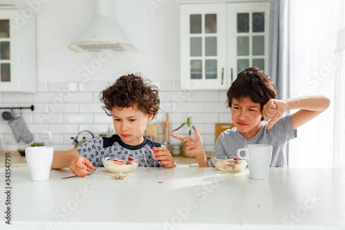 eal brothers have breakfast in the morning in a bright Scandinavian style kitchen with porridge with strawberries
