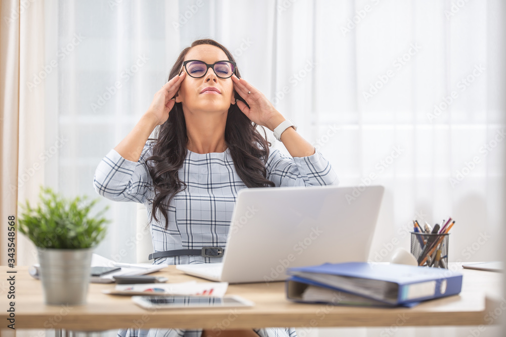 Young woman having eyes closed, fingers on her temples, retrieving mental energy in her work-life balance Young woman having eyes closed, fingers on her temples, retrieving mental energy in her work-life balance