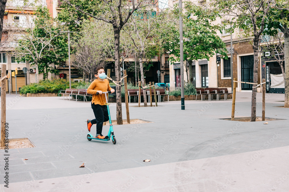 Little boy with a scooter and a  medical mask