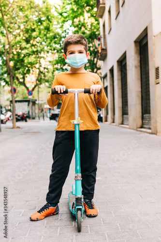 Little boy with a scooter and a medical mask