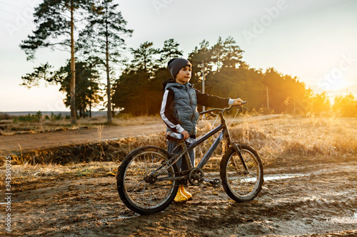 @olga_gimstock photo, nature, people, wheel, fun, dawn, child, leisure, boy, lifestyle, bike 6-7 years old boy stands by the bicycle In the field a rural landscape sunset light.