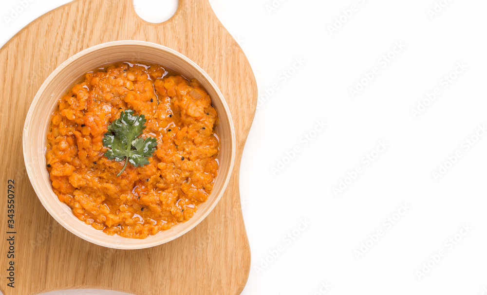 Dhal Indian cream bean soup on a wooden plank on a white background. Copy space. Dhal Indian cream bean soup on a wooden plank on a white background. Copy space.