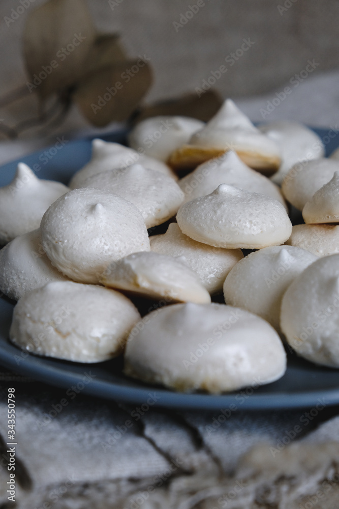 Homemade meringue cookies closeup. Tasty white baked meringues with texture and cracks in the foreground on blue plate