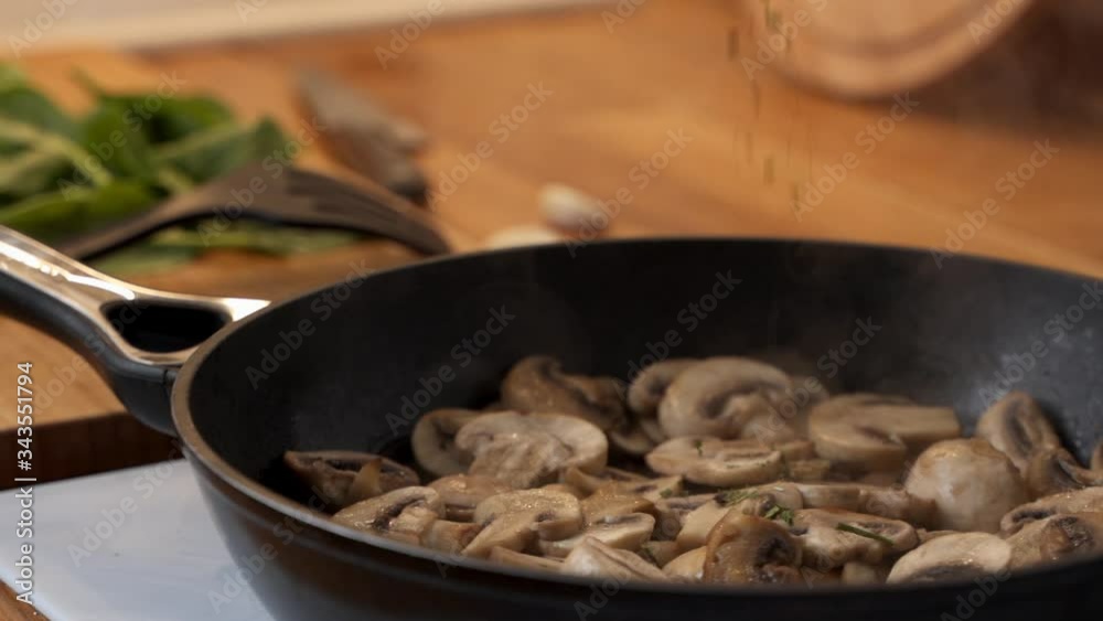 Close-up of a woman sprinkling spices on mushrooms that are fried in a pan. Slow motion video Close-up of a woman sprinkling spices on mushrooms that are fried in a pan. Slow motion video