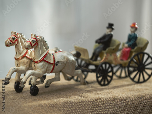 Vintage figurine - horses harnessed to a cart with a coachman and a passenger. Horses in focus