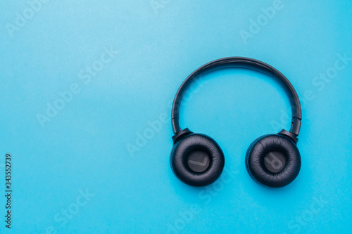 Black headphones on the right side of the photo. From above .Blue background. Copy space