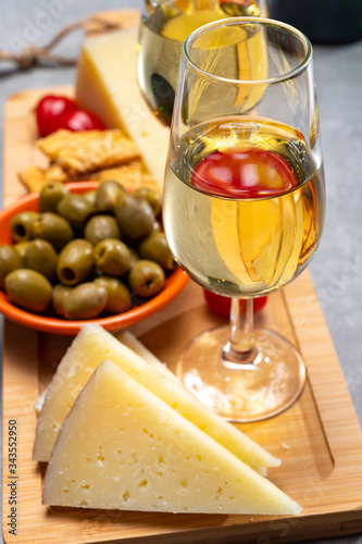 Glasses of dry fino sherry wine served with spanish tapas, manchego cheese, green olives, cheese crackers