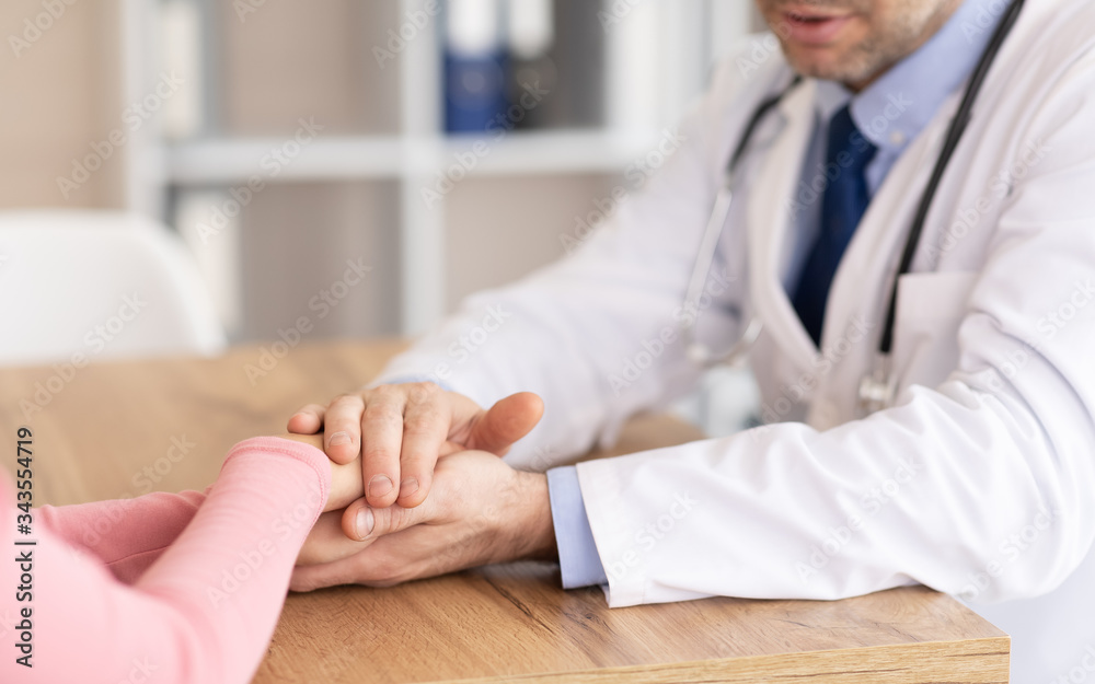 Portrait of mature doctor holding female patient's hands Portrait of mature doctor holding female patient's hands