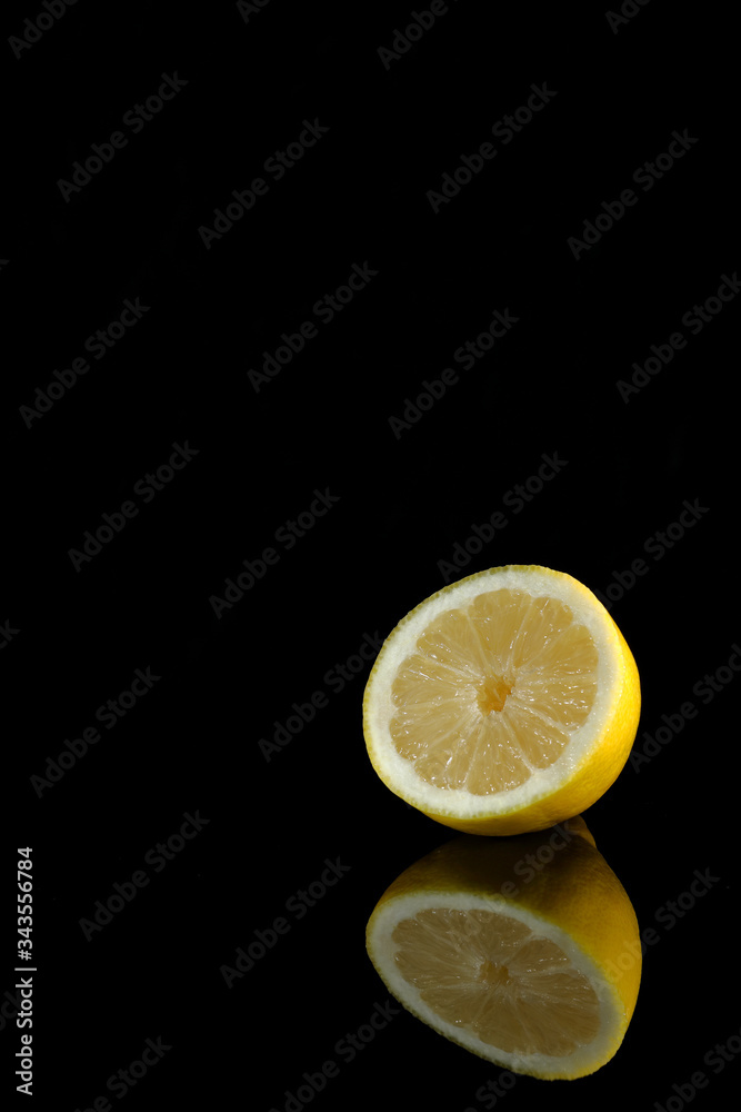 Still life of a lemon cut on black background with reflection Still life of a lemon cut on black background with reflection