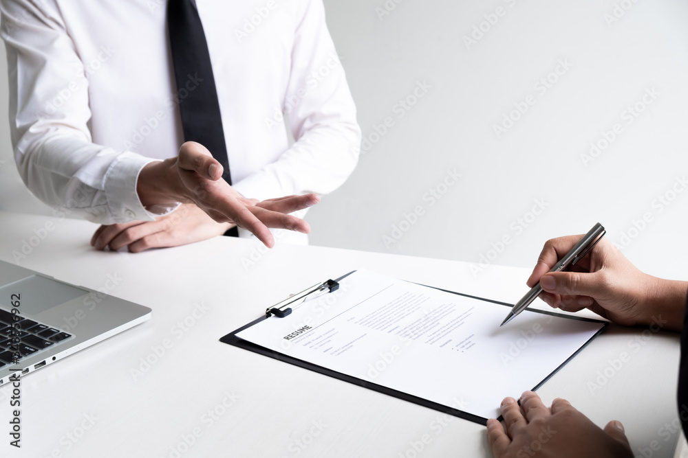 Interview employee is reading and checking a resume with a job applicant in the office. Interview employee is reading and checking a resume with a job applicant in the office.