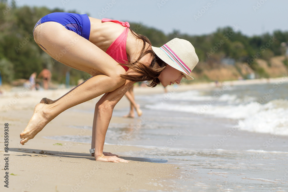 Naklejka premium Young woman practicing yoga on the beach