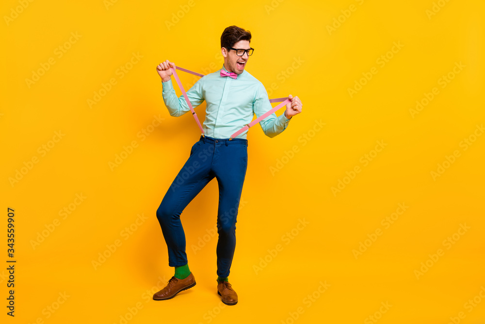 Full length photo of cool stylish guy boyfriend hands hold stretch suspenders festive mood scream excited wear specs shirt bow tie trousers shoes isolated vivid yellow color background Full length photo of cool stylish guy boyfriend hands hold stretch suspenders festive mood scream excited wear specs shirt bow tie trousers shoes isolated vivid yellow color background
