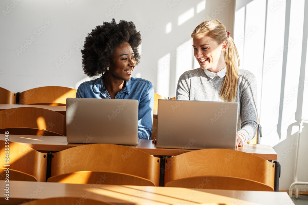 Two female students chatting and taking a break between college classes.
Two female students chatting and taking a break between college classes.
