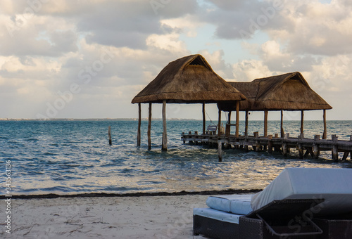 lounge chair on a beach with two palapas  traditional Mexican shelter with thatched roof of palm leaves  