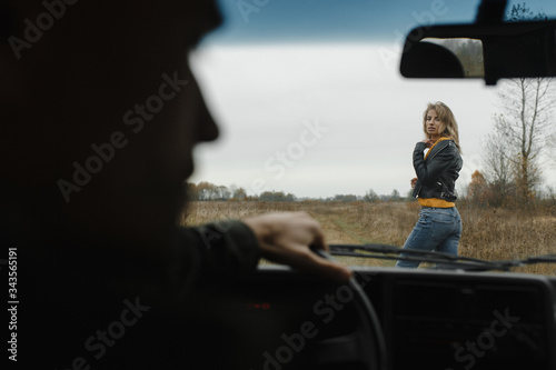 Woman standing in front of the car and man silhouette looking at her © Maksym