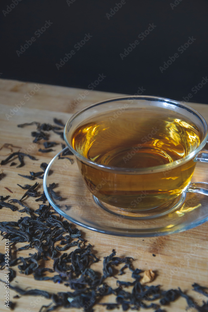 Close up picture cup of tea with dry leaves on the side on wooden background, flat lay composition with empty space for text. Aroma beverage for evening, tea time of chillness, natural taste. Close up picture cup of tea with dry leaves on the side on wooden background, flat lay composition with empty space for text. Aroma beverage for evening, tea time of chillness, natural taste.