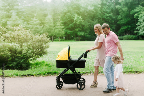 family with a stroller walking in the park on a summer day, family on the weekend