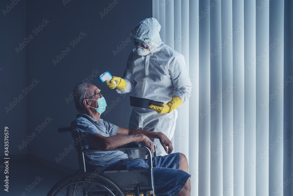 Doctor with protective suit measuring body temperature of an aged male patient Doctor with protective suit measuring body temperature of an aged male patient