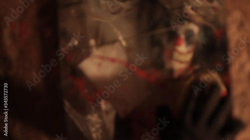 A scarier clown with knife at crude basement with a mirror on the wall