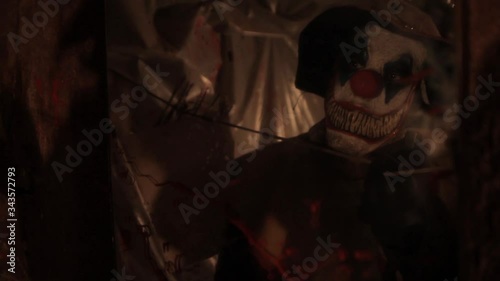 A scarier clown with knife at crude basement with a mirror on the wall