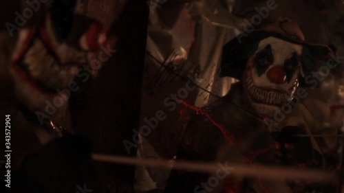 A scarier clown with knife at crude basement with a mirror on the wall