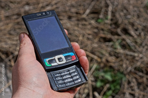 Wallpaper Mural hand holds old black mobile phone outdoors on a sunny day Torontodigital.ca