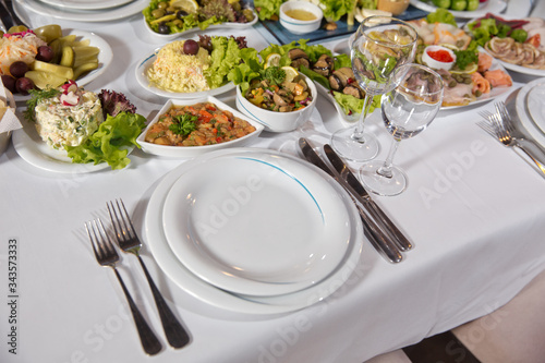 Salads and gums . Set of a dish with spoon, fork and knife on white table.Table setting on white table .