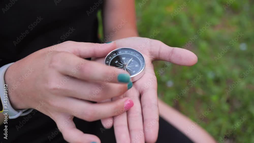 A young girl rotates a metal compass in her hand. A young girl rotates a metal compass in her hand.