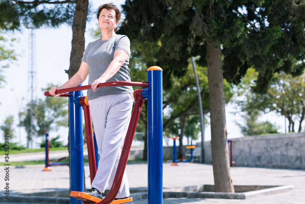 Fototapeta premium Aged woman doing sport exercises on sport ground.