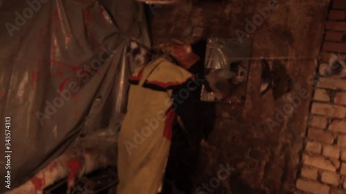 A scarier clown with knife at crude basement with a mirror on the wall