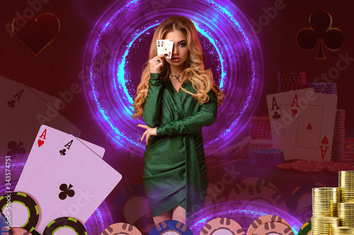 Blonde girl in green dress has covered her eye by two aces, posing on colorful background with neon circles, cards, chips. Poker, casino. Close-up