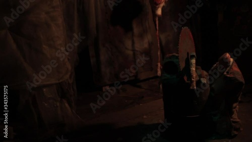 Silhouette of man maniac or killer or horror murderer with chainsaw in hand in dark creepy and spooky room. Criminal robber or rapist concept in thriller atmosphere with  victim girl
