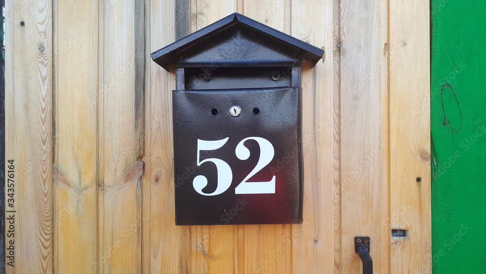 A mailbox in the form of a house hangs on a white wooden door A mailbox in the form of a house hangs on a white wooden door