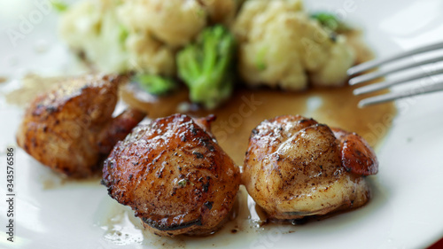 Delicious French dish: scallops cooked in hot butter and flambeed with calvados with steamed vegetables - cauliflower, broccoli, Japanese cabbage on a white plate