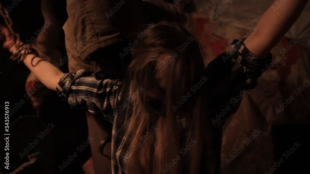 Silhouette of man maniac or killer or horror murderer with chainsaw in hand in dark creepy and spooky room. Criminal robber or rapist concept in thriller atmosphere with  victim girl