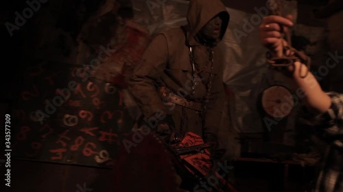 Silhouette of man maniac or killer or horror murderer with chainsaw in hand in dark creepy and spooky room. Criminal robber or rapist concept in thriller atmosphere with  victim girl