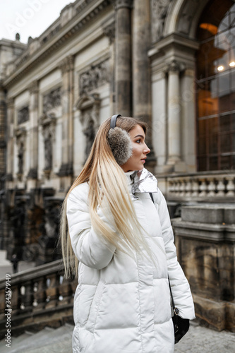 A blonde in a white down jacket is walking in the old city © flywish