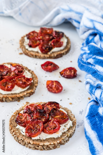Round slices of wholemeal bread with grilled tomatoes on cream cheese