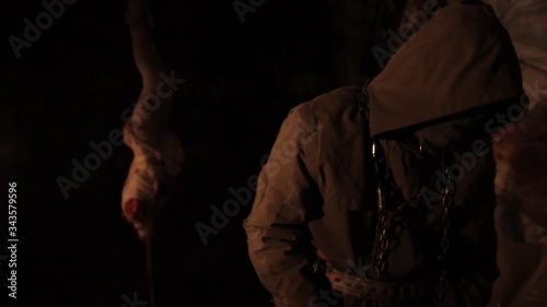 Silhouette of man maniac or killer or horror murderer with chainsaw in hand in dark creepy and spooky room. Criminal robber or rapist concept in thriller atmosphere with  victim girl