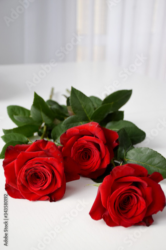 Three red roses on white table in light house