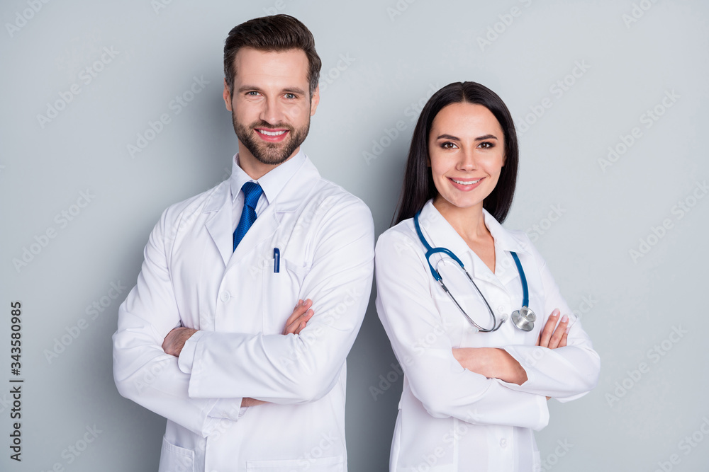 Photo of handsome doc guy lady patient consultation virology clinic stand back-to-back toothy smiling arms crossed experienced doctors wear lab coats isolated grey color background Photo of handsome doc guy lady patient consultation virology clinic stand back-to-back toothy smiling arms crossed experienced doctors wear lab coats isolated grey color background