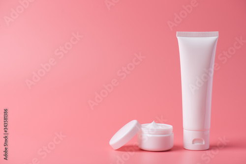 Advertising homemade minimal creative concept. Photo of one plastic tube with cleanser and open round jar with cap lid isolated over pastel background with empty blank space