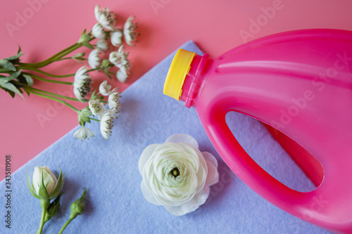Cleaning supplies and white flowers on a pink background.