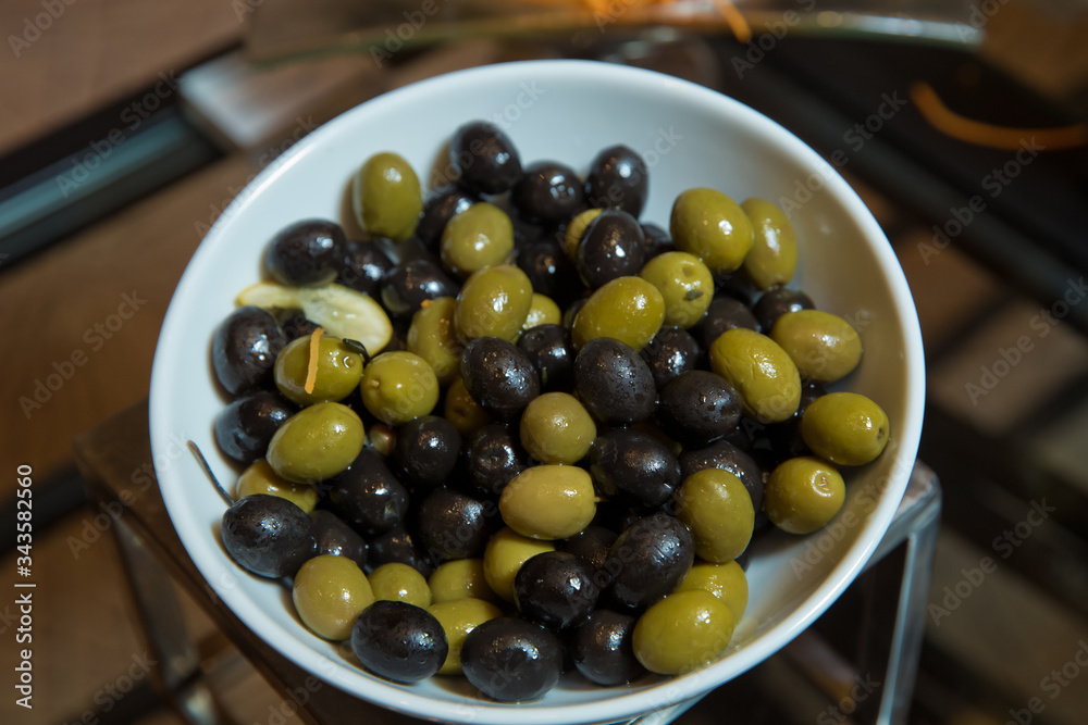 Top view with space for text . Green and black olives in a white ceramic bowl . Top view with space for text . Green and black olives in a white ceramic bowl .