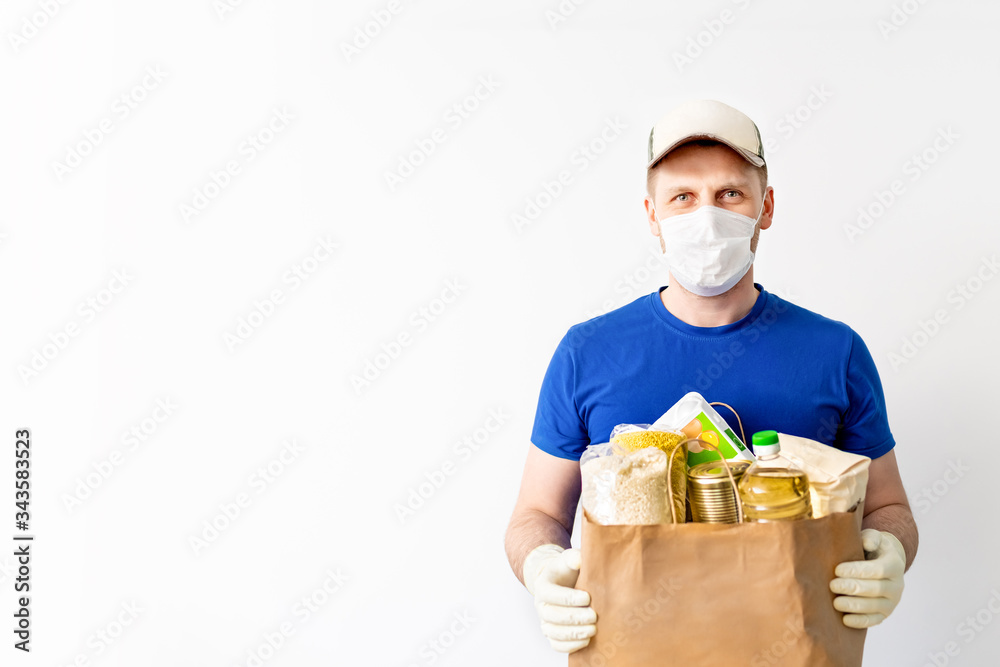 Happy Delivery man in blue cap blank tshirt uniform glove hold donations bag on isolated on white background. Service quarantine pandemic coronavirus virus 2019-ncov. Donation food. Space for text Happy Delivery man in blue cap blank tshirt uniform glove hold donations bag on isolated on white background. Service quarantine pandemic coronavirus virus 2019-ncov. Donation food. Space for text