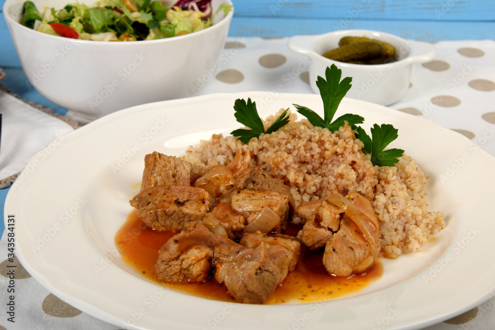 pieces of meat with sauce and barley on a white plate pieces of meat with sauce and barley on a white plate